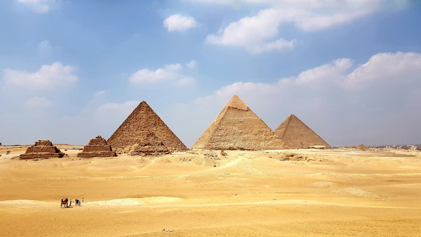 The pyramids of Giza rising from golden sand under a blue sky